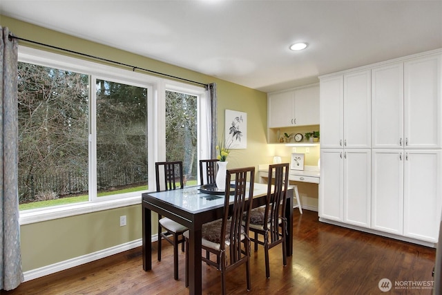 dining space with a wealth of natural light, dark wood finished floors, built in study area, and baseboards