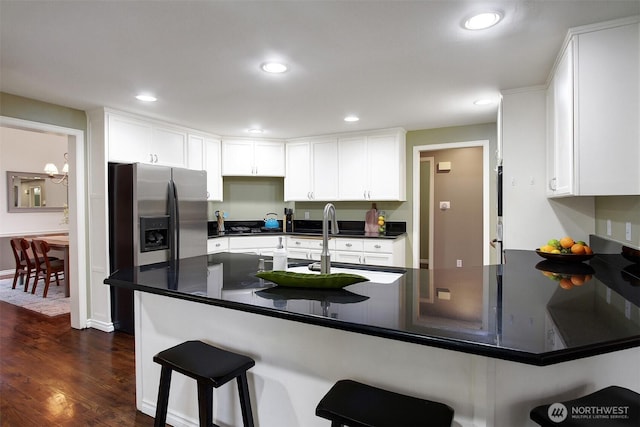 kitchen with white cabinetry, a peninsula, a kitchen breakfast bar, and dark wood-style floors