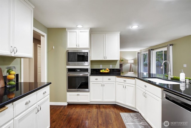 kitchen featuring a sink, white cabinets, dark wood finished floors, and stainless steel appliances