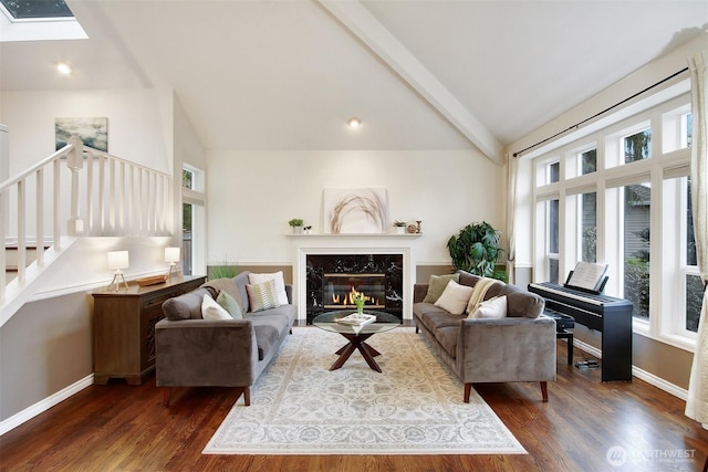 living area featuring plenty of natural light, a fireplace, a skylight, and baseboards