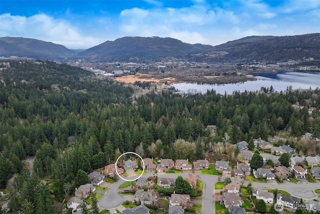 aerial view featuring a forest view and a water and mountain view