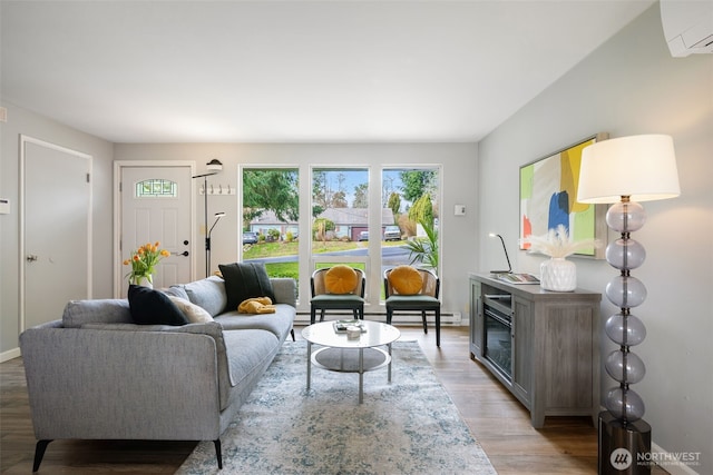 living area featuring a wall mounted air conditioner, light wood-type flooring, and baseboards