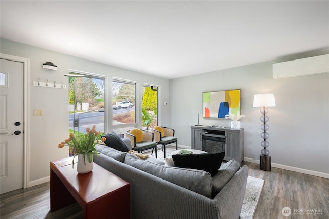 living room with a wall mounted air conditioner, baseboards, and wood finished floors