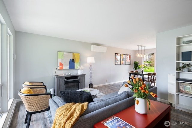 living area featuring a wall mounted air conditioner, baseboards, and wood finished floors