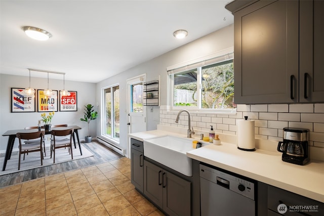 kitchen featuring a wealth of natural light, a sink, tasteful backsplash, light countertops, and dishwasher