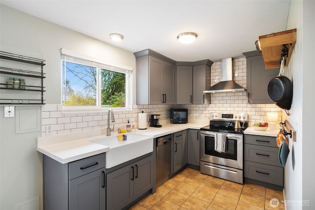 kitchen with gray cabinets, a sink, stainless steel electric range, wall chimney range hood, and dishwasher