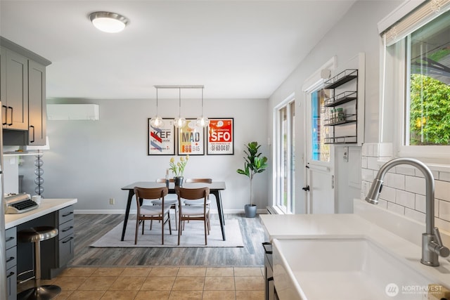 kitchen featuring gray cabinets, a wall mounted air conditioner, light countertops, and a sink