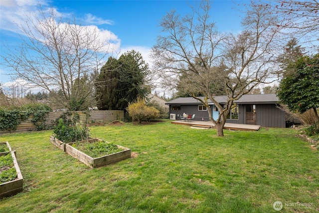 view of yard with a garden, a deck, and fence