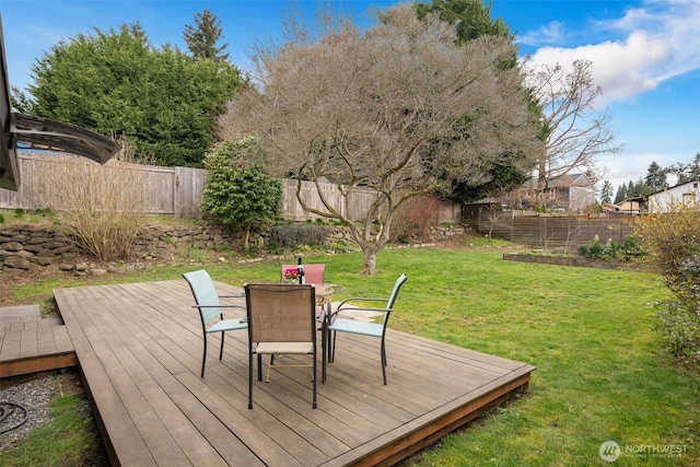 wooden terrace with a fenced backyard, a lawn, and outdoor dining space