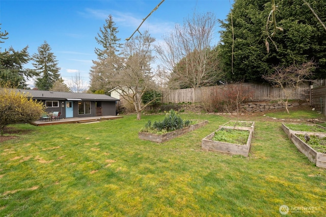 view of yard featuring a vegetable garden, a deck, and fence