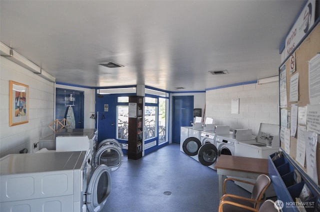 common laundry area with visible vents and concrete block wall