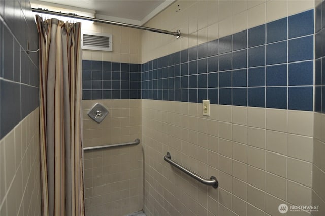 full bath featuring visible vents and tiled shower