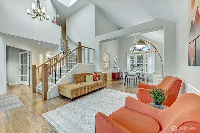 living room featuring wood finished floors, high vaulted ceiling, stairs, french doors, and a chandelier