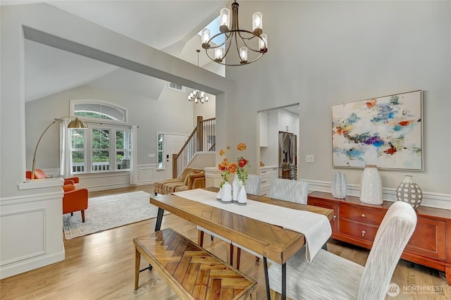 dining space featuring an inviting chandelier, stairway, light wood-type flooring, and lofted ceiling