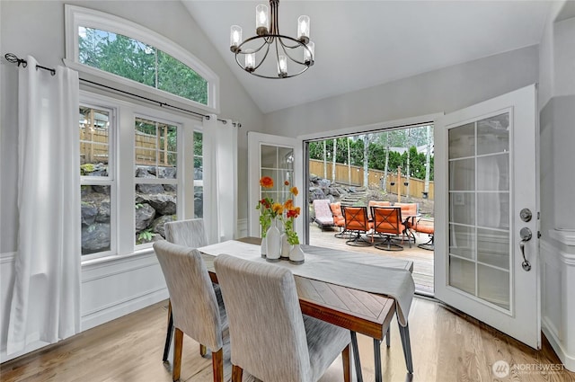 dining space with light wood-style floors, an inviting chandelier, and vaulted ceiling