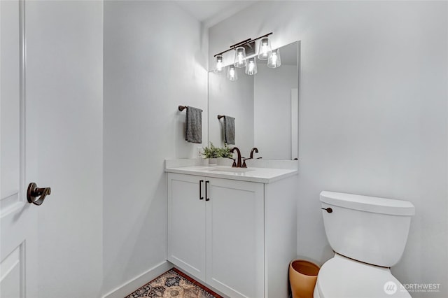 bathroom featuring toilet, vanity, and baseboards