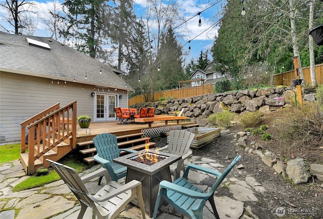 view of patio / terrace featuring french doors, fence, a wooden deck, and an outdoor fire pit