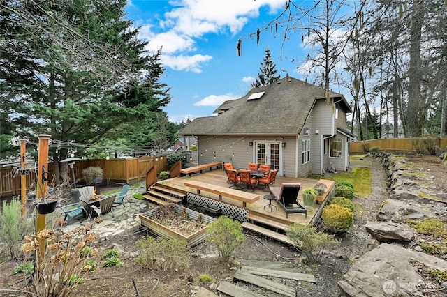 back of house featuring a deck, a fenced backyard, a shingled roof, and an outdoor fire pit