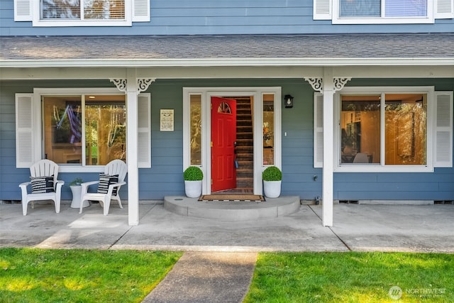 view of exterior entry featuring crawl space, roof with shingles, and a porch