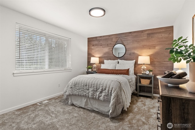 bedroom with visible vents, wood walls, carpet flooring, baseboards, and an accent wall