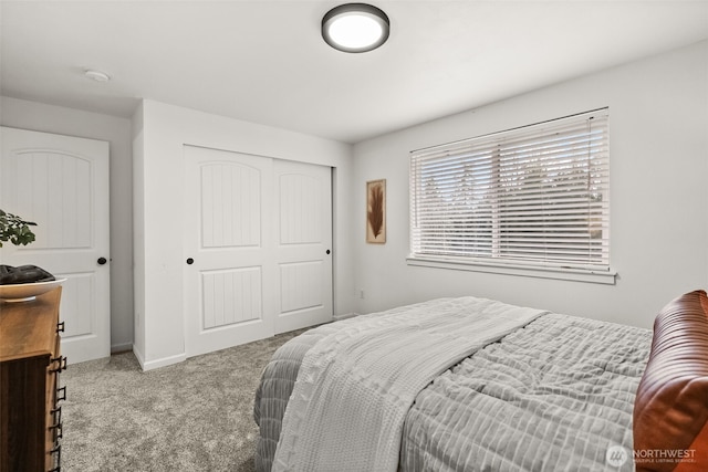 carpeted bedroom with a closet and baseboards