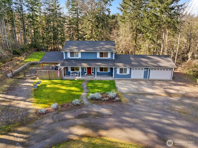 view of front of property featuring a front yard, fence, driveway, covered porch, and a garage