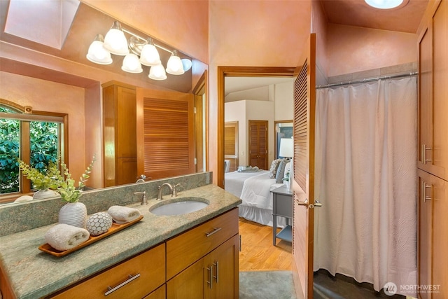 bathroom featuring ensuite bath, wood finished floors, a shower with shower curtain, lofted ceiling, and vanity