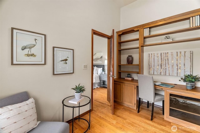 office with light wood-style floors and built in desk