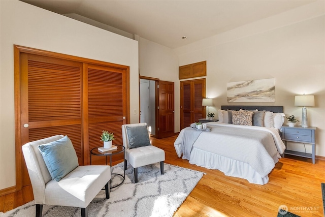 bedroom with wood finished floors, multiple closets, and baseboards