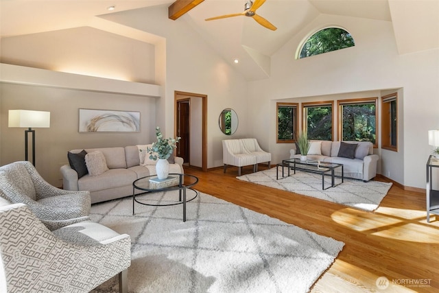 living room with ceiling fan, wood finished floors, baseboards, and high vaulted ceiling