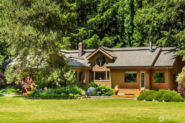 view of front facade featuring a shingled roof, a front lawn, and a chimney