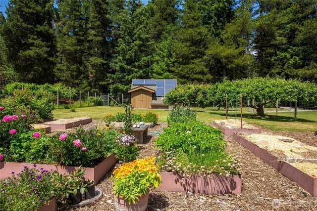 view of yard featuring a garden, a storage unit, an outbuilding, and fence