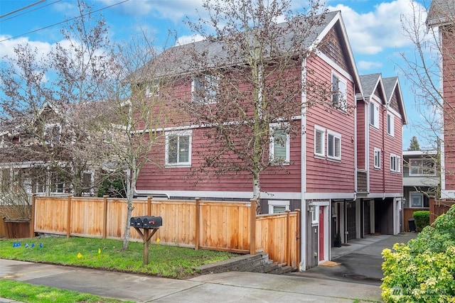 view of property exterior featuring concrete driveway, fence, and a garage