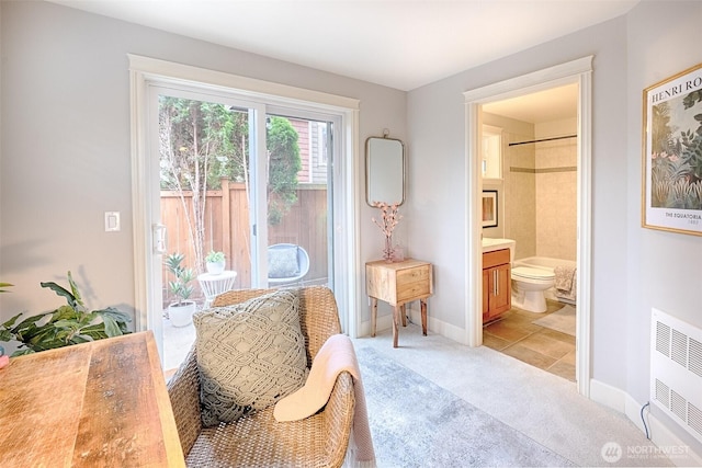 sitting room with radiator, baseboards, and light colored carpet