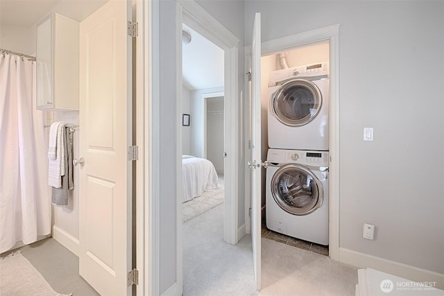 clothes washing area featuring laundry area, light colored carpet, and stacked washer and clothes dryer