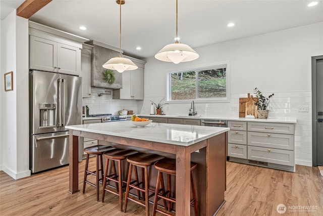 kitchen with light wood finished floors, light stone counters, gray cabinets, stainless steel appliances, and a sink