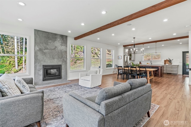 living area featuring a high end fireplace, beam ceiling, light wood-style flooring, and recessed lighting