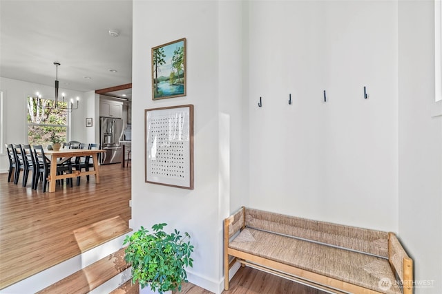 mudroom with baseboards, light wood-type flooring, and an inviting chandelier