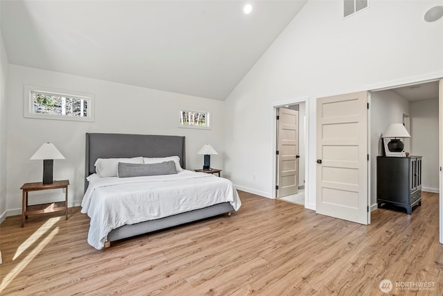 bedroom with visible vents, baseboards, high vaulted ceiling, and light wood-style flooring