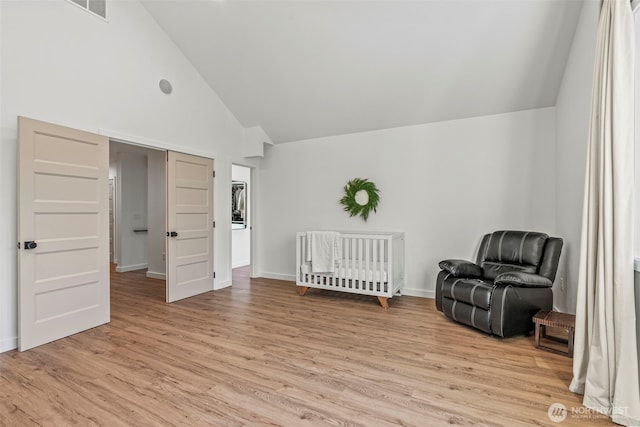 living area with baseboards, light wood-style floors, and high vaulted ceiling