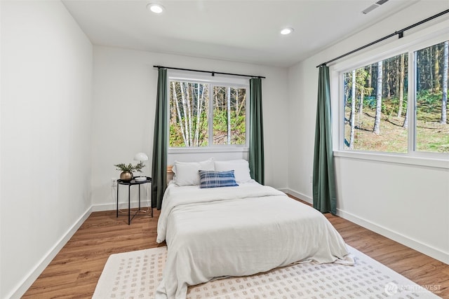 bedroom with recessed lighting, visible vents, baseboards, and wood finished floors