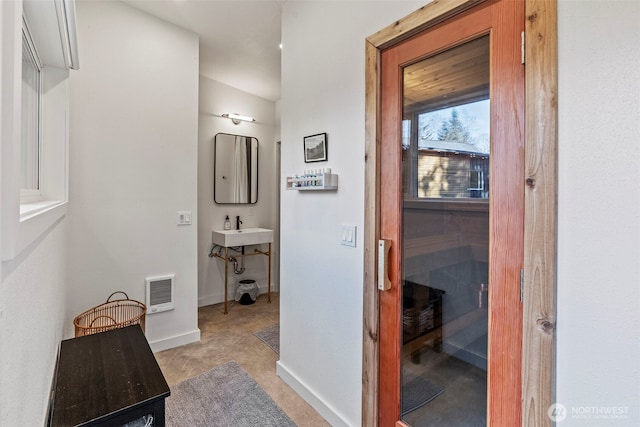 hallway with visible vents, baseboards, and a sink