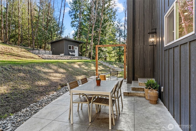 view of patio featuring outdoor dining space, an outbuilding, and a shed