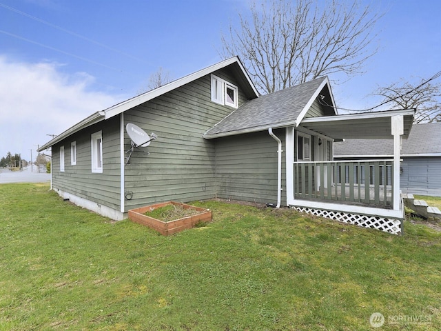 view of side of property featuring a yard, roof with shingles, and a deck