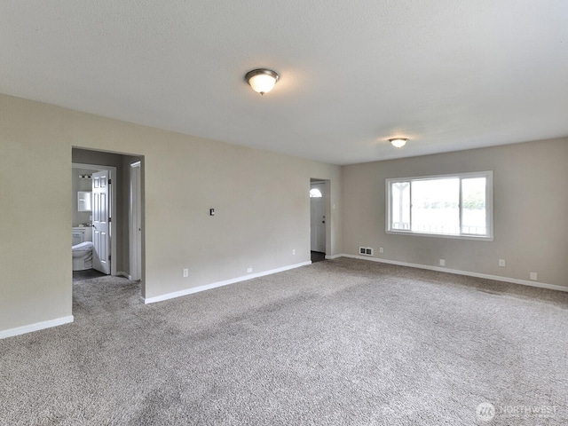 empty room featuring visible vents, carpet flooring, a textured ceiling, and baseboards