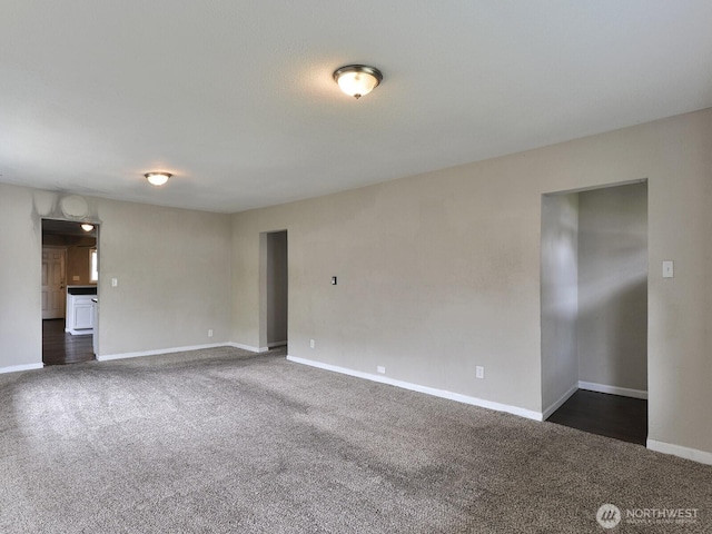 unfurnished living room with dark carpet and baseboards