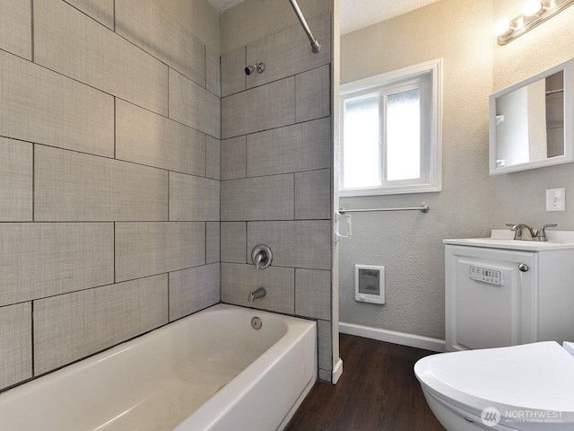 full bath with wood finished floors,  shower combination, baseboards, vanity, and a textured wall