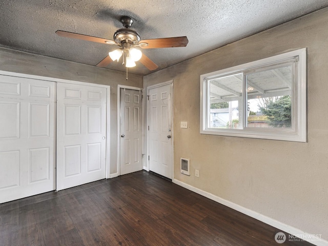 unfurnished bedroom featuring dark wood finished floors, a ceiling fan, baseboards, and a textured ceiling