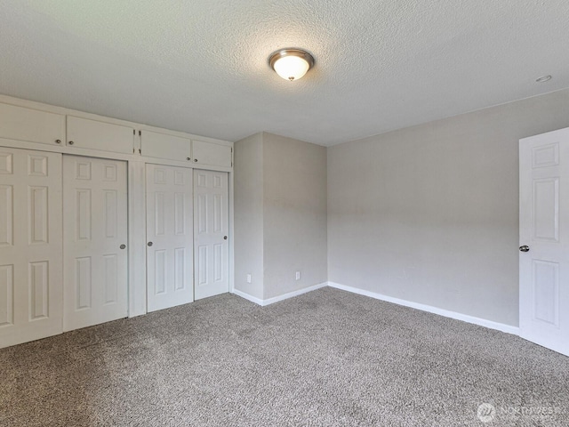 unfurnished bedroom featuring carpet flooring, baseboards, a closet, and a textured ceiling