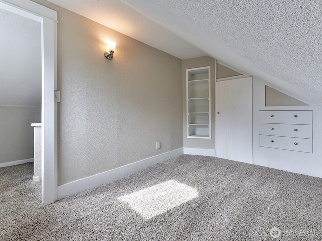 additional living space with lofted ceiling, baseboards, carpet floors, and a textured ceiling